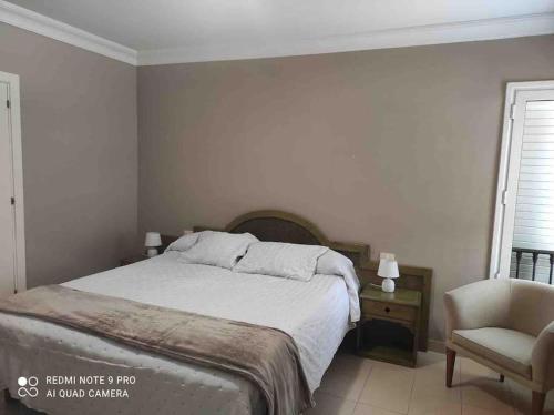 um quarto branco com uma cama e uma cadeira em Magnifico y acogedor apartamento, zona privilegiada vistas al mar em Puerto de la Cruz