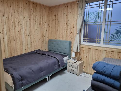 ein Schlafzimmer mit einem Bett, einem Stuhl und einem Fenster in der Unterkunft Amy House in Jeju-do