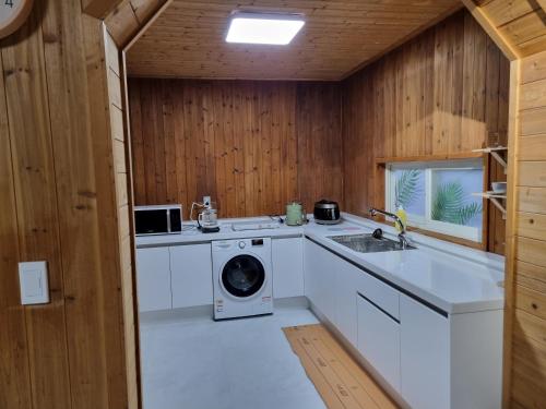 eine Küche mit einer Waschmaschine und einem Waschbecken in der Unterkunft Amy House in Jeju-do