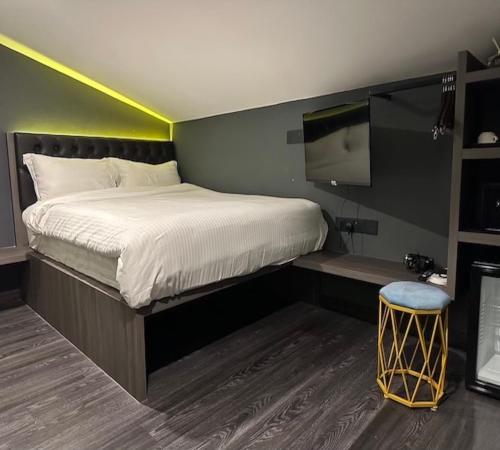 a bedroom with a bed with a tv and a stool at HOTEL JJH - newly opened near BUGIS in Singapore