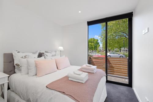 a bedroom with a white bed with towels on it at Latimer View Apartment in Christchurch