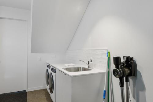 a white kitchen with a sink and a washing machine at Latimer View Apartment in Christchurch