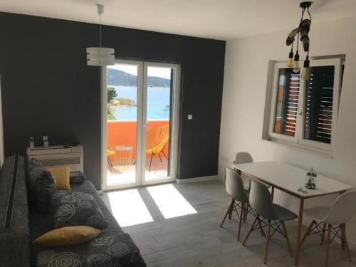 ein Wohnzimmer mit einem Sofa und einem Tisch mit Stühlen in der Unterkunft Apartments Delfin - sea view in Prvić Šepurine