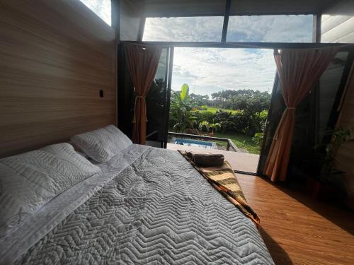 1 dormitorio con cama grande y ventana grande en Ruztico glamping, en Villavicencio