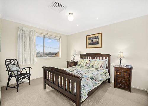 Un dormitorio con una cama y una silla y una ventana. en Floreat, en Sawtell