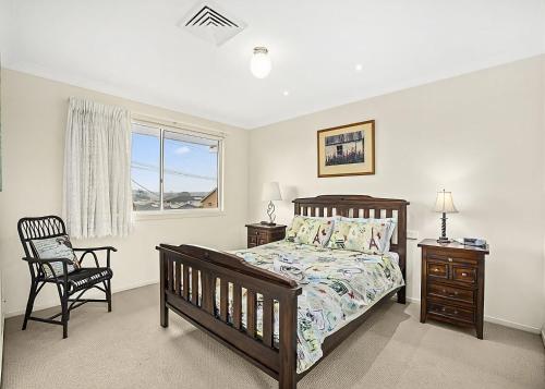 a bedroom with a bed and a chair and a window at Floreat in Sawtell