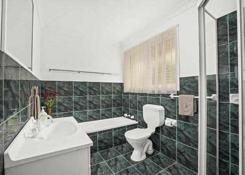 Un baño con un lavabo blanco y un inodoro. en Floreat, en Sawtell