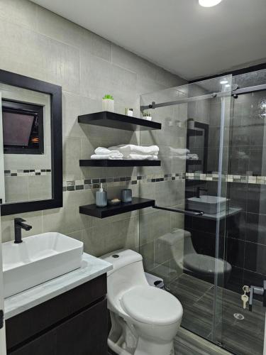 y baño con aseo, ducha y lavamanos. en apartamento de lujo, en Cuenca