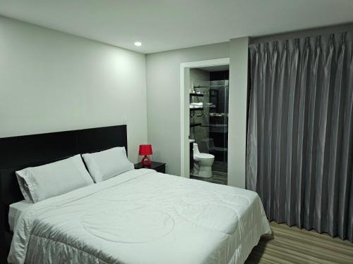 1 dormitorio con 1 cama blanca grande y baño en apartamento de lujo, en Cuenca
