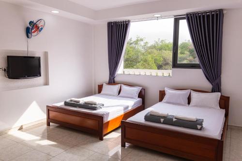 a bedroom with two beds and a tv and a window at Hoa Cúc Phương Hotel Dĩ An - Bình Dương in Dĩ An