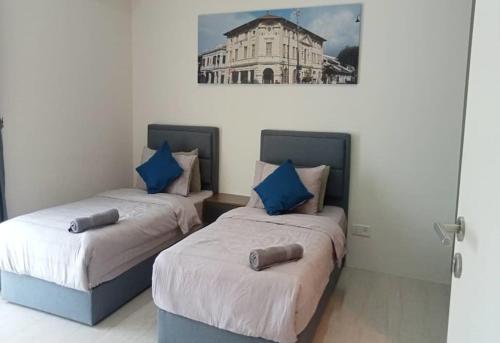 two beds in a room with a picture on the wall at By The Sea Batu Ferringhi in Batu Ferringhi