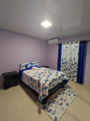 1 dormitorio con 1 cama y una ventana con cortinas azules en Coral, en Fantino