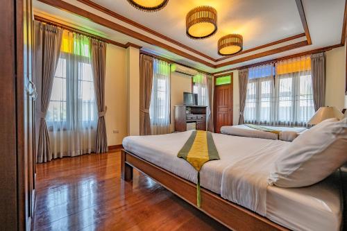 a bedroom with two beds and windows at มนต์เมืองเชียงใหม่ รีสอร์ต Monmuang Chiangmai Resort in Hang Dong