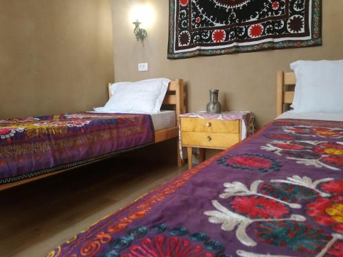 a room with two beds and a table and a rug at Azaliya Hostel in Samarkand