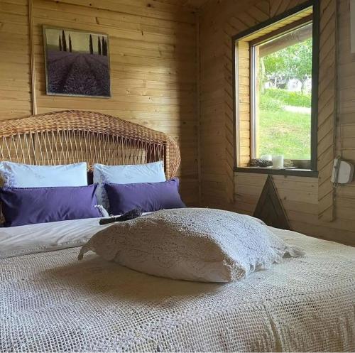 ein Schlafzimmer mit einem Bett mit lila Kissen und einem Fenster in der Unterkunft Lavender Valley in Perekrestnoye