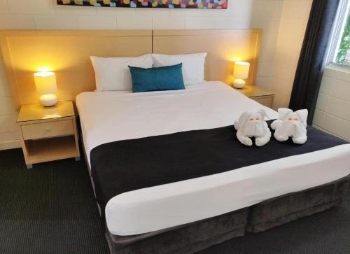 two stuffed animals sitting on top of a bed at Coconut Grove Holiday Apartments in Darwin