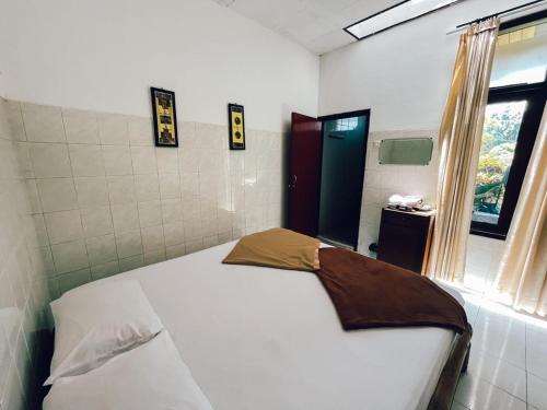 a bedroom with a white bed with a window at d'BACA Homestay in Batu