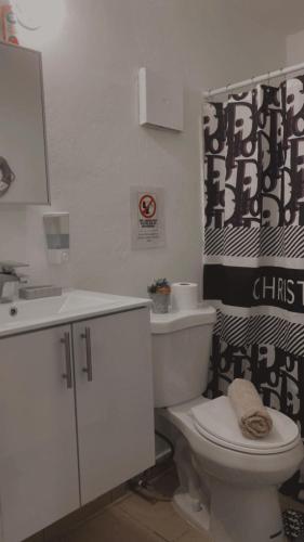 a bathroom with a white toilet and a sink at Jardines Home in Trujillo Alto