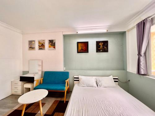 a bedroom with a bed and a blue chair at MINA HOUSE Airport Apartment in Ho Chi Minh City