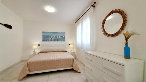 a white bedroom with a bed and a mirror at Villa Barbara Fra i Pini in Lignano Sabbiadoro