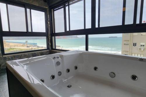a bath tub in a bathroom with a view of the ocean at מבנים בים 75 Suites at sea in Haifa