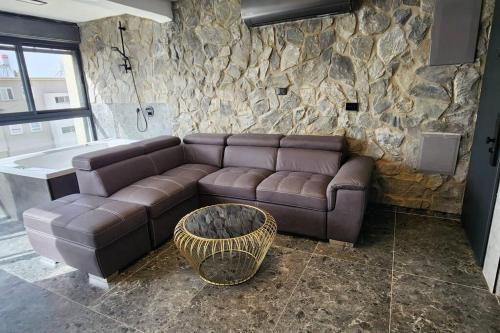 a living room with a brown couch and a stone wall at מבנים בים 75 Suites at sea in Haifa