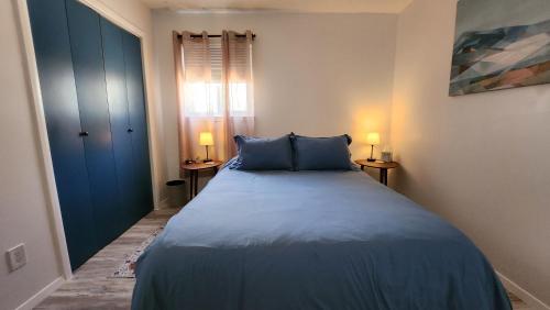a bedroom with a bed with blue sheets and two lamps at The Lilly Pad II in Albuquerque