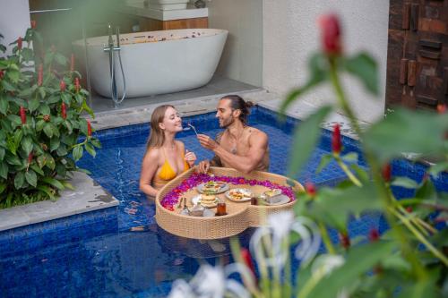 a man and woman in a bathtub in a pool at Teratai Villa Canggu by Ini Vie Hospitality in Canggu