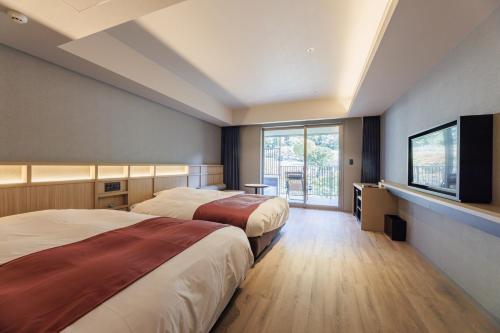 two beds in a room with a flat screen tv at Minakami Onsen Aratashi Minakami in Minakami