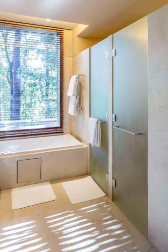 a bathroom with a shower and a tub and a window at Six Senses Vana - A Wellness Retreat in Dehradun