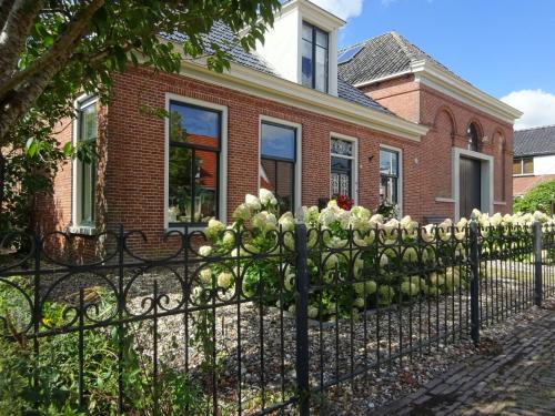 a fence in front of a house with flowers on it at d' âld skoalle - Sfeervol appartement in oude school. in Wijtgaard
