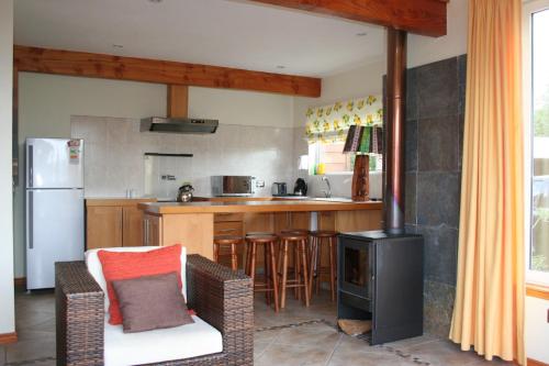 a kitchen with a stove and a counter with a refrigerator at Cabañas Portal de las Rosas in Puerto Varas