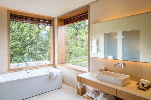 デヘラードゥーンにあるSix Senses Vana - A Wellness Retreatのバスルーム(バスタブ、シンク、鏡付)