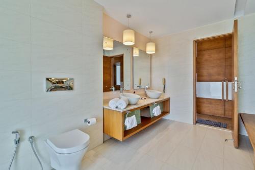 a bathroom with a toilet and a sink and a mirror at StayVista at Tarika's Seascapes with Pool & Home Theatre in Dabolim