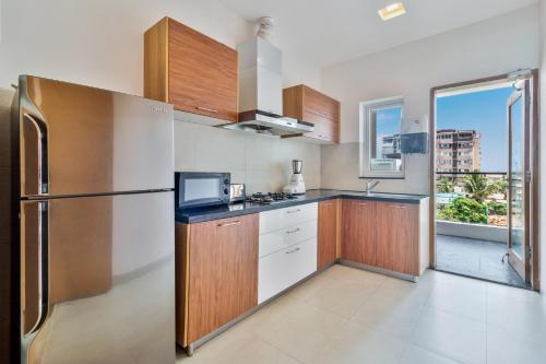 a kitchen with wooden cabinets and a refrigerator at Tarika's Seascapes by VEO - Part of StayVista in Dabolim