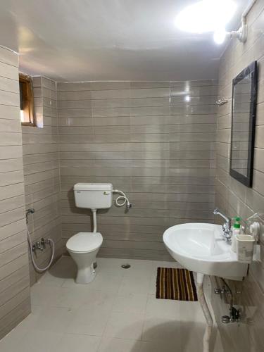 a bathroom with a white toilet and a sink at Brook Cottage in Champawat