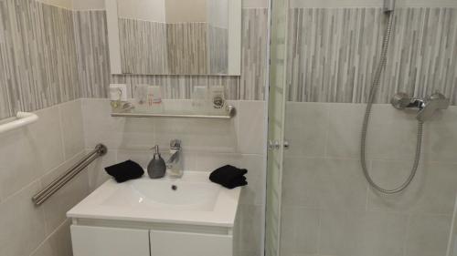 a white bathroom with a sink and a shower at Serge le belge sejour chez l habitant in Lézignan-Corbières