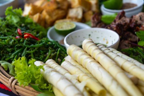 a table with a bunch of vegetables and a basket of food at Truong Nhan Tram Tau Homestay in Cham Ta Lao