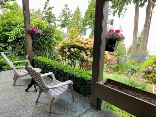 a patio with two chairs and flowers in a garden at Waterfront Eagle Nest in Nanaimo