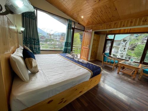 a bedroom with a bed with a large window at Royal View Inn in Manāli