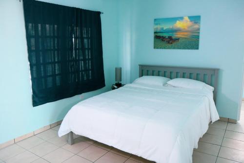 - une chambre avec un lit blanc et un mur bleu dans l'établissement MAVS COMBATE BEACH CLUB, à Cabo Rojo