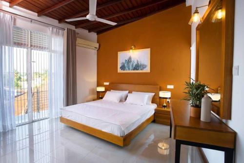a bedroom with a bed and a table and a window at The Greens Luxury Boutique Villa in Karagampitiya