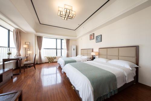 um quarto de hotel com duas camas e uma secretária em Livetour Hotel Luogang Wanda Plaza Guangzhou em Guangzhou