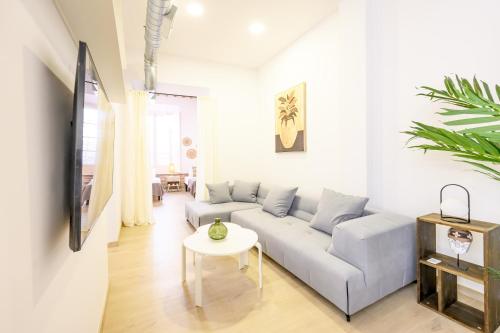 salon z kanapą i stołem w obiekcie Modern 3 bedroom, city center with patio & high ceilings by 10ToSea w Maladze