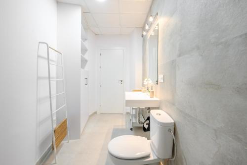 biała łazienka z toaletą i umywalką w obiekcie Modern 3 bedroom, city center with patio & high ceilings by 10ToSea w Maladze