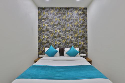 a bedroom with a bed with blue and yellow pillows at Hotel Shivaay in Ahmedabad