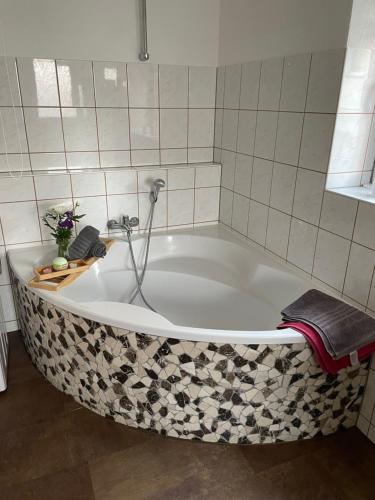 a bath tub in a bathroom with a tile wall at Jeanny´s Ferienwohnung in Thale