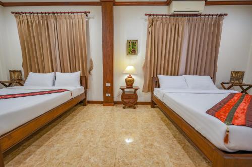 a bedroom with two beds and a lamp and curtains at มนต์เมืองเชียงใหม่ รีสอร์ต Monmuang Chiangmai Resort in Hang Dong