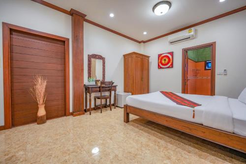 a bedroom with a bed and a table and a desk at มนต์เมืองเชียงใหม่ รีสอร์ต Monmuang Chiangmai Resort in Hang Dong