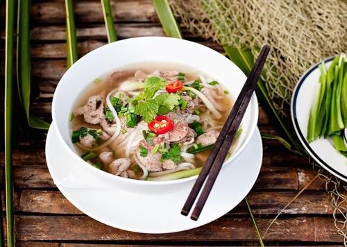 Phong Nha Midtown hotel في فونغ نها: وعاء من الحساء على طاولة مع عيدان الطعام